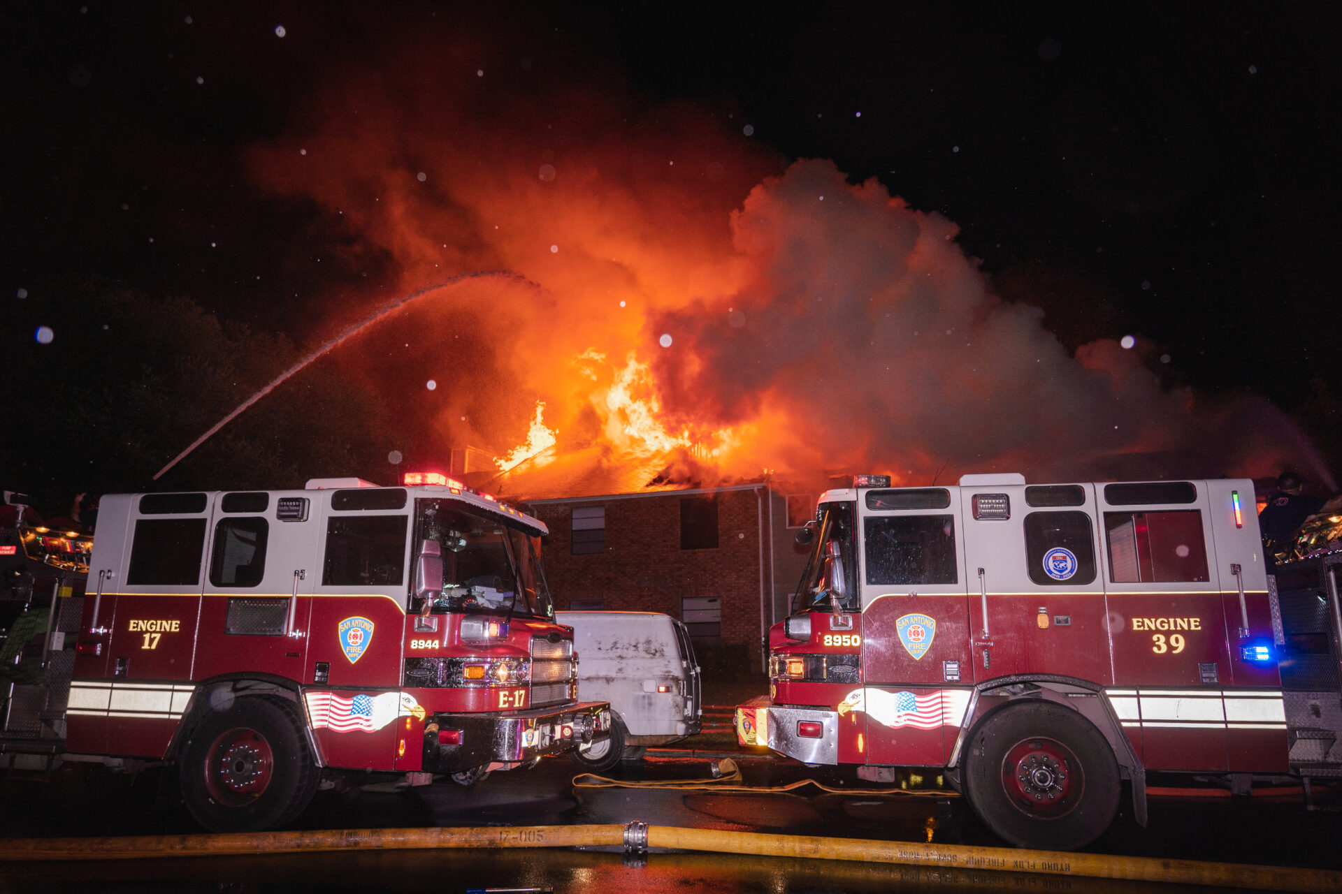 Two firetrucks are parked in front of a fire.